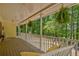 Inviting covered porch with swing and hanging ferns offers a relaxing outdoor space with views of the wooded landscape at 4950 Creel Rd, Chattahoochee Hills, GA 30213