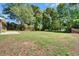 Spacious backyard with grass, mature trees, and a partial view of the home's brick exterior at 606 Evergreen Dr, Woodstock, GA 30188