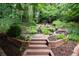 Backyard oasis with stone steps, lush landscaping, a bridge, and a waterfall at 161 Highgrove Dr, Suwanee, GA 30024
