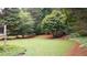 Backyard features an expansive lawn with lush trees and landscaping at 161 Highgrove Dr, Suwanee, GA 30024