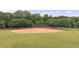 Community baseball field with well-kept grass and red clay, enclosed by a chain-link fence for sports and recreation at 161 Highgrove Dr, Suwanee, GA 30024