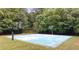 Full-sized basketball court with two hoops and a blue and white patterned surface, surrounded by trees at 161 Highgrove Dr, Suwanee, GA 30024