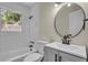 Clean bathroom with a white vanity, round mirror, and a shower-tub combination at 2115 Pinehurst Dr, East Point, GA 30344