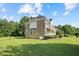 Expansive backyard featuring lush green lawn, mature trees, and the home's exterior with brick and light siding at 327 Awendaw Cir, Ellenwood, GA 30294