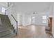 Open-concept living room with a fireplace, wood-look floors, and neutral walls, adjacent to the staircase at 327 Awendaw Cir, Ellenwood, GA 30294