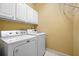Well-lit laundry room with white washer and dryer, cabinetry and tile floor at 2610 Chadwick Rd, Marietta, GA 30066