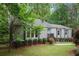 Quaint one-story home with a light-blue front door, landscaped front yard, and lush trees in the background at 3006 Alberta Dr, Marietta, GA 30062