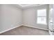 Neutral bedroom featuring a tray ceiling, a window, neutral walls and carpet, and white trim at 4041 Ash Tree St, Snellville, GA 30039