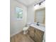 Bathroom with a wood vanity cabinet, marble countertop, modern faucet, and wood-look floors at 681 Burtons Cv, Hampton, GA 30228