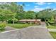 Ranch-style home with a brick facade, expansive lawn, mature trees, and paved driveway leading to the residence at 124 Chaseland Rd, Atlanta, GA 30328