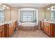Bright bathroom featuring a large soaking tub framed by tilework and dual vanities with wood cabinets at 2871 Trailing Ivy Way, Buford, GA 30519