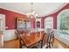 Formal dining room with a large wooden table, chandelier, and red accent wall at 2871 Trailing Ivy Way, Buford, GA 30519
