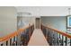Hallway with a carpeted floor, decorative railing, and view of a chandelier at 2871 Trailing Ivy Way, Buford, GA 30519