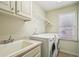 Well-lit laundry room with a sink, a folding counter, washer, dryer, and shelving at 2871 Trailing Ivy Way, Buford, GA 30519