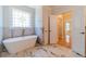 Luxury bathroom showcasing a soaking tub, marble floors, and a decorative window at 980 Windsor Place Cir, Grayson, GA 30017