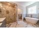 Elegant bathroom with marble shower, soaking tub, and decorative window at 980 Windsor Place Cir, Grayson, GA 30017