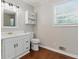 A full bathroom with sleek, white cabinets offers plenty of storage, while wood floors and a window add classic charm at 3544 Chestatee Dr, Marietta, GA 30062