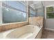 Bathroom featuring a large bathtub, tile surround, and natural light from a window at 3642 Fowler Rdg, Douglasville, GA 30135