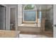 Well-lit bathroom showcasing a soaking tub with a large window and a glass-enclosed shower at 3642 Fowler Rdg, Douglasville, GA 30135