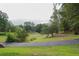Scenic golf course view with a paved path, lush greenery, mature trees, and a glimpse of a house in the distance at 3642 Fowler Rdg, Douglasville, GA 30135