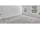 A simple bedroom with neutral gray walls, large windows, and light-colored carpet flooring at 4238 Sir Dixon Dr, Fairburn, GA 30213