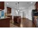 Well-lit kitchen with dark wood cabinets, granite countertops, and a kitchen island with pendant lighting at 4238 Sir Dixon Dr, Fairburn, GA 30213