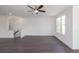 Living room with dark wood floors, a ceiling fan, a staircase, and a large window at 502 Healy Dr # 76, Cumming, GA 30040
