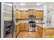 Well-lit kitchen with wood cabinets, stainless steel appliances, and center island with hardwood floors at 275 Blue Pointe Ct, Suwanee, GA 30024