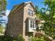 Side view of brick townhome features mature trees, landscaping, and stairway leading to the front door at 3786 Alstead Manor Way, Suwanee, GA 30024