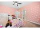 This bedroom has pink walls and polka dots and a ceiling fan at 132 Shellbark Dr, Mcdonough, GA 30252