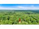 Aerial view of a charming house surrounded by a canopy of trees with a blue sky backdrop at 5689 Woodland Dr, Acworth, GA 30102
