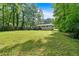 Expansive backyard with lush green grass, mature trees, and a view of the back of the home at 5689 Woodland Dr, Acworth, GA 30102