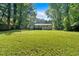 Expansive backyard with lush green grass, mature trees, and a view of the back of the home at 5689 Woodland Dr, Acworth, GA 30102