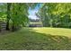 Expansive backyard with lush green grass, mature trees, and a view of the back of the home at 5689 Woodland Dr, Acworth, GA 30102