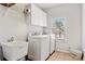 Well-lit laundry room with washer, dryer, storage cabinets, utility sink, and a window at 388 Golf Crest Dr, Acworth, GA 30101