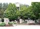 Community entrance featuring stone pillars, lush landscaping, and a clock tower in the background at 7699 Cabrini Pl, Fairburn, GA 30213