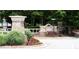Community entrance featuring stone pillars, lush landscaping, and a clear street view at 7699 Cabrini Pl, Fairburn, GA 30213