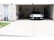 Two-car garage featuring a modern white car, with outdoor space including lawn and exterior door at 7699 Cabrini Pl, Fairburn, GA 30213
