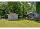 View of backyard with two storage sheds amidst green grass and mature trees at 15 Porter Cir, Hampton, GA 30228