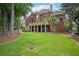 Expansive backyard view of a brick home with large deck and landscaped lawn at 8250 Saint Marlo Fairway Dr, Duluth, GA 30097