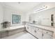 Bright bathroom with a soaking tub beneath a stained glass window at 8250 Saint Marlo Fairway Dr, Duluth, GA 30097
