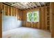 Unfinished room features wood framing, insulation, concrete walls, and a window for natural light at 1604 Niskey Lake Rd, Atlanta, GA 30331