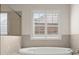 Bright bathroom featuring a soaking tub and shower and window with privacy shutters at 3317 Sweetleaf Ln, Buford, GA 30519