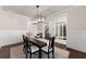 Dining room with black table, white chairs, dark floor, and modern light fixture at 3317 Sweetleaf Ln, Buford, GA 30519