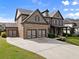 Brick home featuring a driveway, two-car garage, a manicured lawn, and walkway at 3317 Sweetleaf Ln, Buford, GA 30519