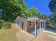 Brick home with covered porch, showcasing the side with grey siding and a concrete walkway at 1150 Goldsmith Rd, Stone Mountain, GA 30083