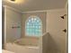 Bathroom featuring a jetted tub under an arched window, and a white tiled shower at 730 Redlion Run, Alpharetta, GA 30022