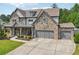 Handsome stone and siding home featuring a three-car garage and inviting front porch with seating at 776 Amos Ln, Kennesaw, GA 30152