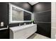 Modern bathroom with a double vanity, sleek black walls, and illuminated mirror at 860 Peachtree Ne St # 2801, Atlanta, GA 30308