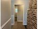Hallway featuring neutral walls, an exposed brick accent wall, and a glimpse of an exterior door at the end at 172 Camp Sunrise Nw Rd, Cartersville, GA 30121